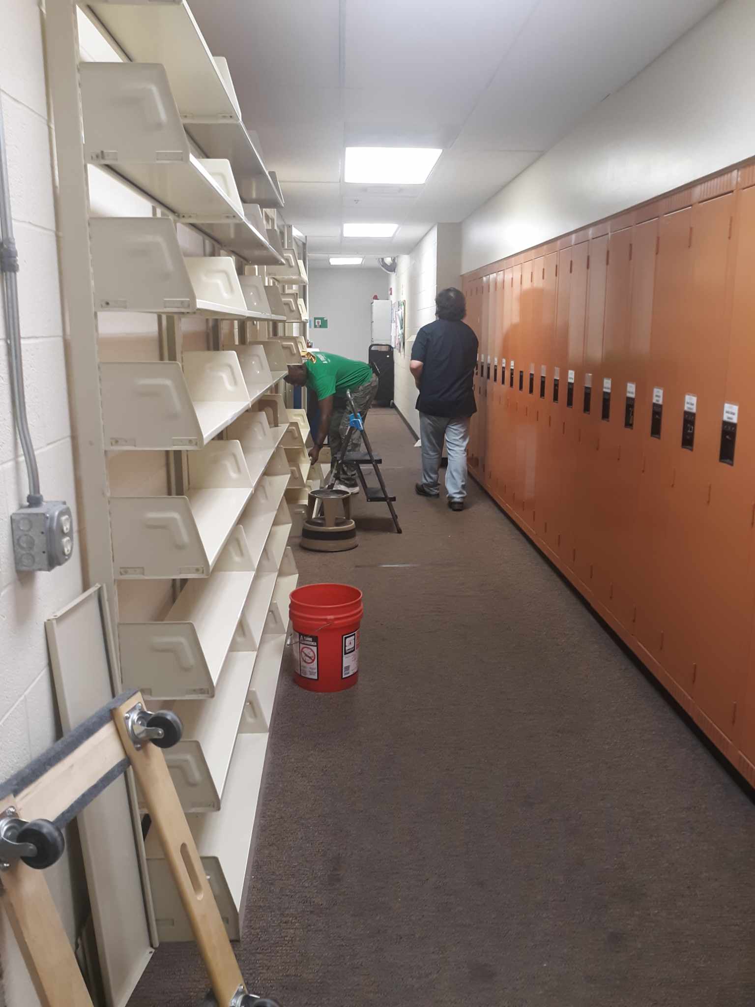 Staff taking down the Book Club Kit shelve that stood in a back hallway in the staff area.