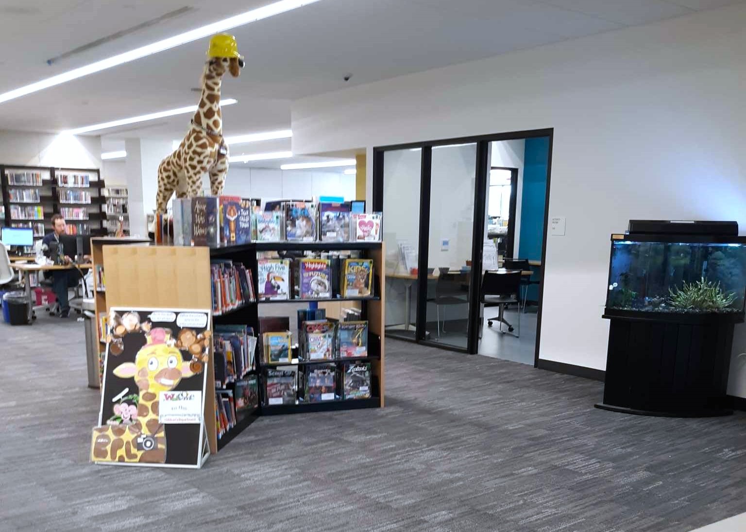 Entrance to the childrens department with a book display, stuffed giraffe and giraffe artwork