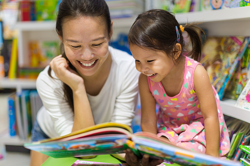 Mom and daughter reading picture book together