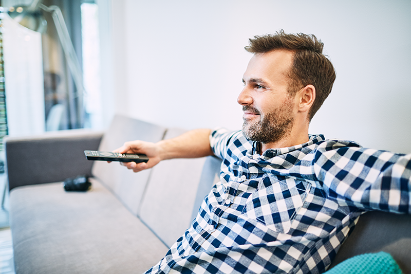 Man sitting on couch and watching DVD