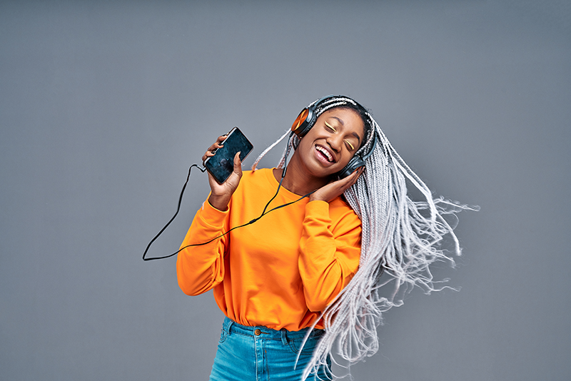 Young woman listening to music on her phone and dancing along