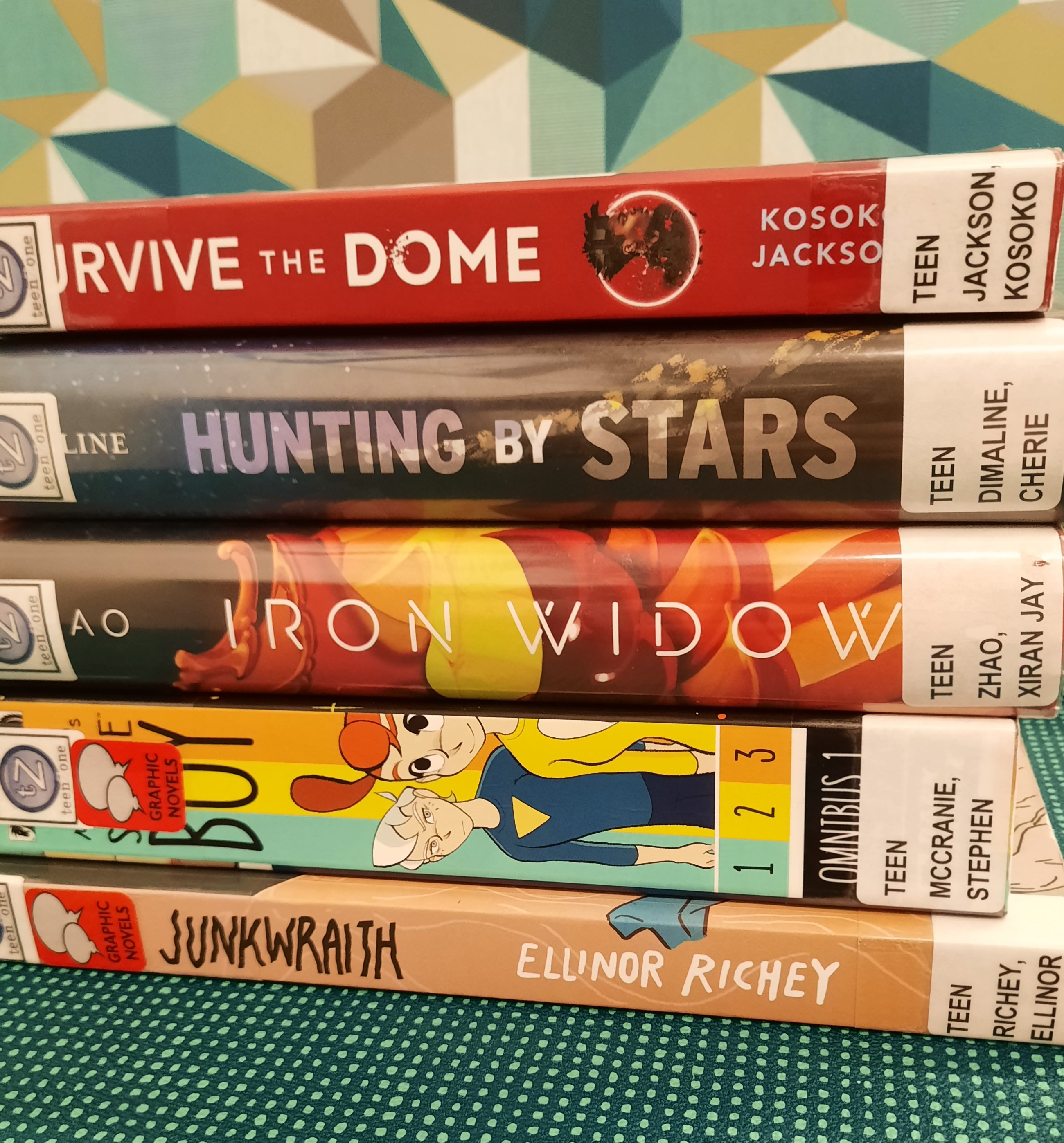 2025 January Book Stack Stack of books. The Spines read from top to bottom "Survive the Dome," "Hunting by Stars," "Iron Widow," "Space Boy," and "Junkwraith"