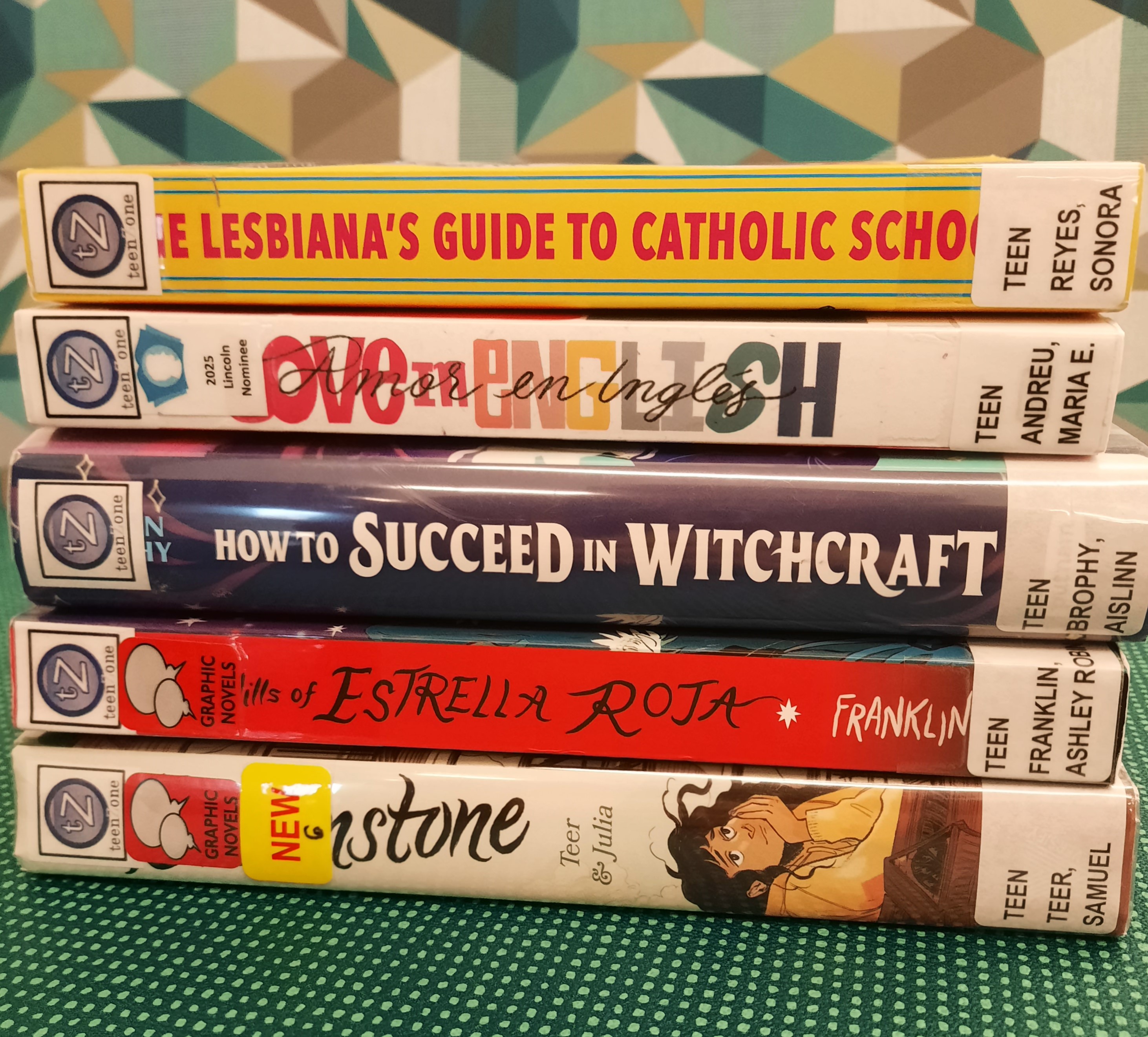 2025 October Book Stack Book Stack showing the following titles: "The Lesbiana's Guide to Catholic School," "Love in English," "How to Succeed in Witchcraft," "The Hills of Estrella Roja" and "Brownstone"