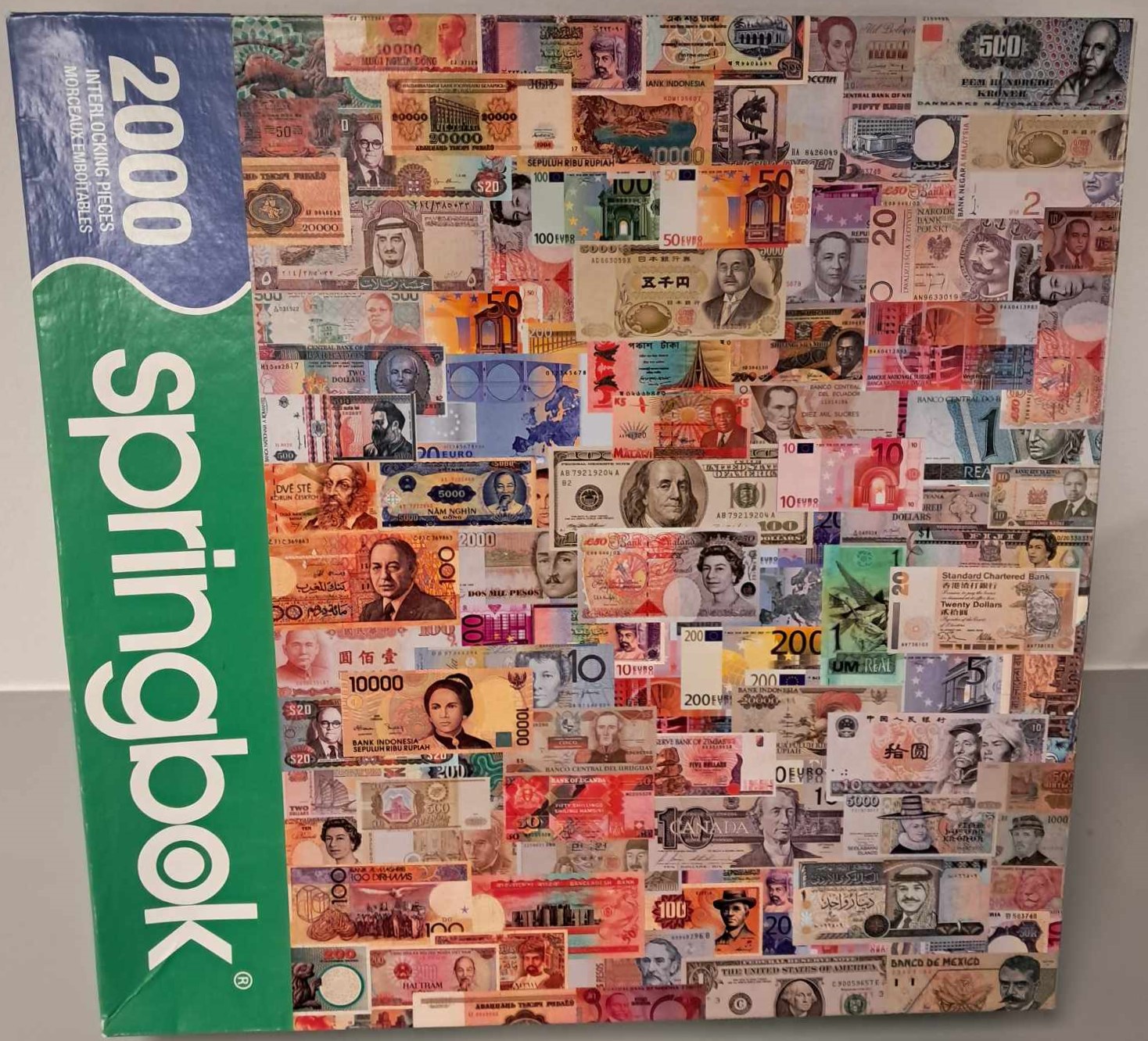 Puzzle cover showing a collage of different bills from different countries of different amounts and colors.