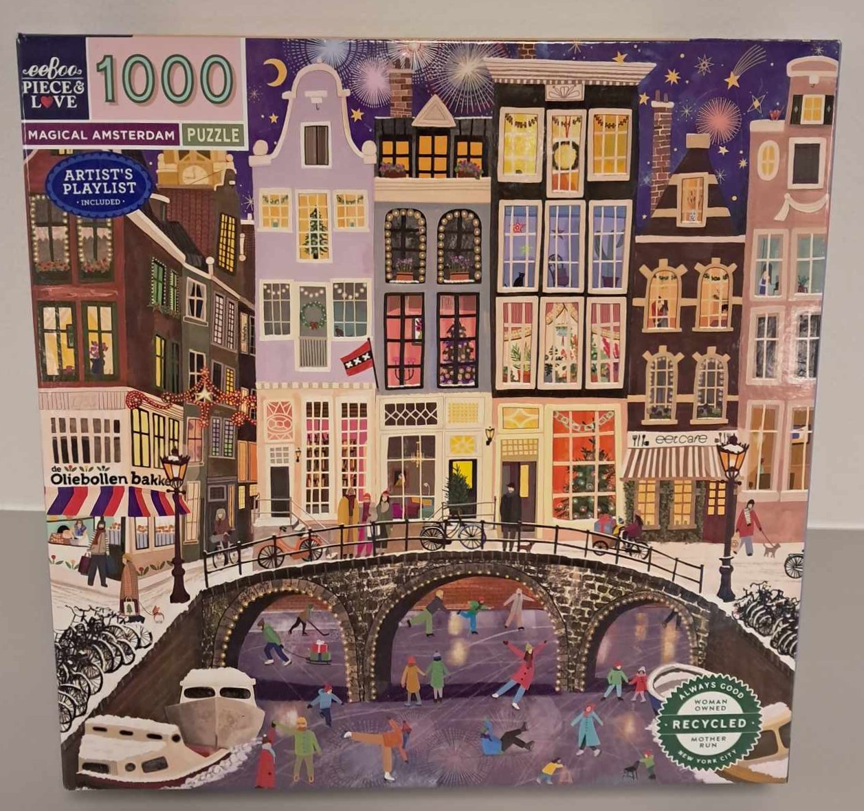 Puzzle cover showing an artistic drawing of multiple buildings near a bridge that people are walking across.