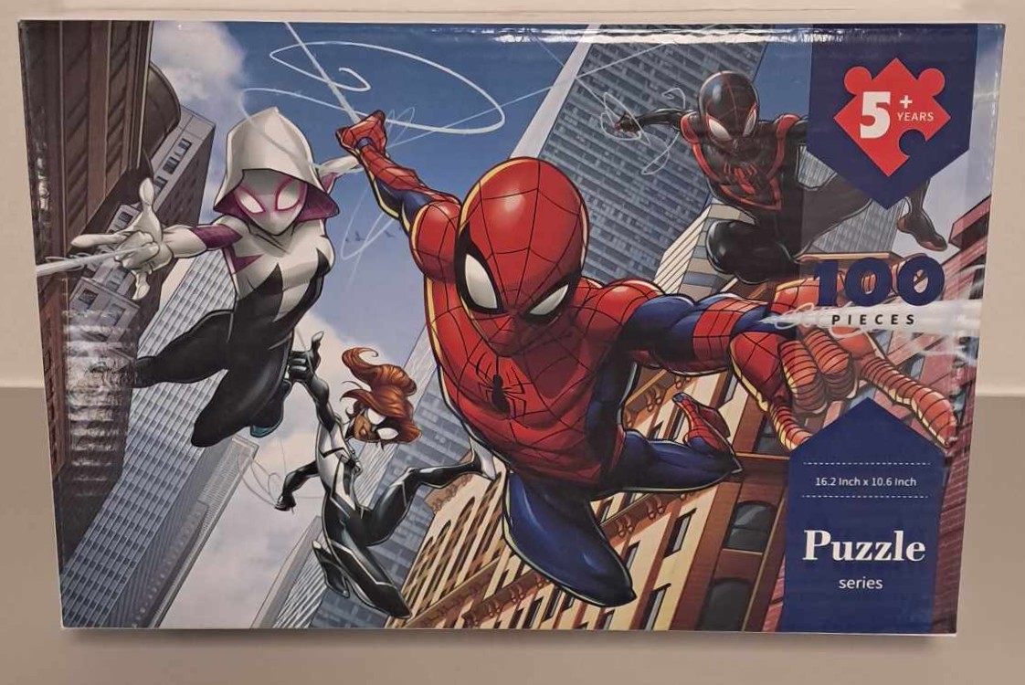 Puzzle cover showing an illustration of Spiderman and his friends swinging through the city.